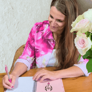 Rosa schreibt in einem Notizbuch. Am Tisch stehen Rosen.
