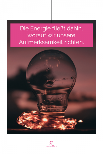 Dunkle Glühbirne mit leuchtender Lichterkette nachts. Zitat-Text: "Die Energie fließt dahin, worauf wir unsere Aufmerksamkeit richten."